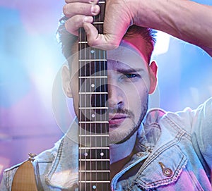 Portrait of a handsome performer holding a guitar