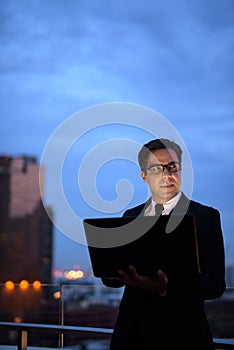 Handsome Persian businessman against view of the city at night