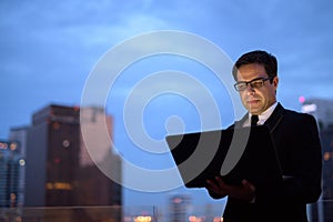 Handsome Persian businessman against view of the city at night