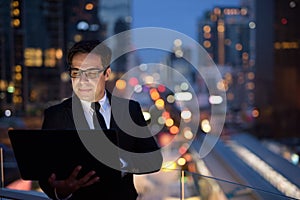 Handsome Persian businessman against view of the city at night