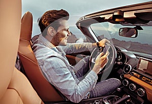 Portrait of a handsome, rich man driving his convertible car photo