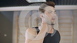 Portrait of handsome runner listening music on treadmill machine in fitness club
