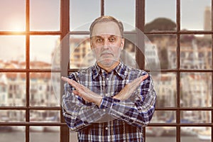 Portrait of a handsome serious man shows reject gesture with arms cross.