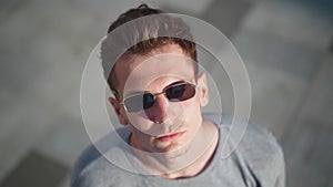 Portrait Handsome serious tough man dresses his black sunglasses and looks at camera. Caucasian stylish guy on blurred background