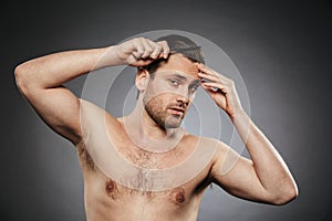Portrait of a handsome shirtless man combing his hair