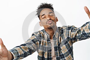Portrait of handsome silly african american man, close eyes and pucker lips to kiss you, stretch out hands for hug