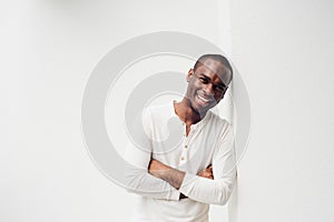 Handsome smiling african american man leaning against wall with arms crossed