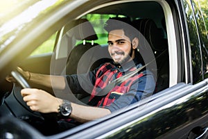 Portrait of an handsome smiling indian s man driving his car with white shirt