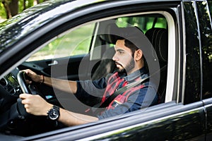 Portrait of an handsome smiling indian s man driving his car with white shirt