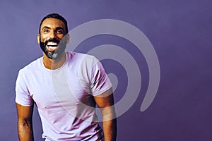 portrait of a handsome smiling man with beard and mustache purple shirt on a gray looking away at copy space background