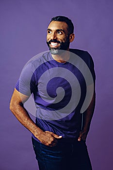 portrait of a handsome smiling man with beard and mustache purple shirt on a gray looking at camera space background