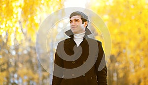 Portrait of handsome smiling man wearing a black coat jacket in sunny autumn