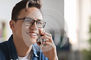 Portrait of handsome smiling young guy wearing eyeglasses talking on mobile phone