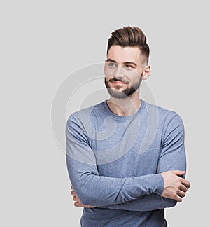 Portrait of handsome smiling young man with folded arms isolated on gray background. Joyful cheerful men with crossed hands