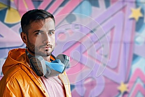 Portrait of handsome street artist staying on his graffiti painting background