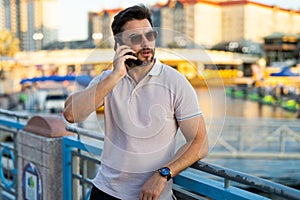 Portrait of handsome stylish man chatting on phone in big city. Sexy man in casual clothes talking on phone on the