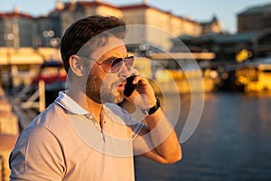 Portrait of handsome stylish man chatting on phone in big city. Sexy man in casual clothes talking on phone on the