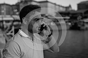 Portrait of handsome stylish man chatting on phone in big city. Sexy man in casual clothes talking on phone on the