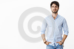 Portrait of handsome successful male entrepreneur in stylish shirt smiling self-assured standing in confident pose with