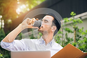 Portrait of handsome successful man drink coffee. Happy man take coffee break as he sitting at his laptop computer working