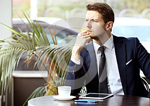 Portrait of handsome successful man drink coffee and look to the digital tablet screen sitting in coffee shop