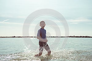 Portrait of handsome teen boy running in neoprene swimsuit in sea