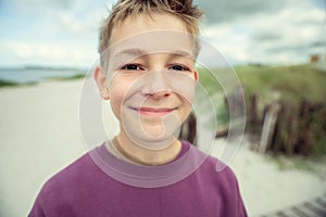 Portrait of handsome teenage boy on beach with white sand at summer day