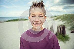 Portrait of handsome teenage boy on beach with white sand at summer day