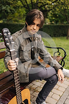 Portrait of handsome teenage boy playing guitar outdoor. Boy using classic guitar. Male alone making music