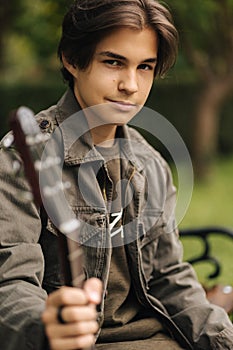 Portrait of handsome teenage boy playing guitar outdoor. Boy using classic guitar. Male alone making music