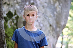 Portrait of handsome teenager boy in casual clothes smiling in camera on green sunny background
