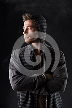 Portrait of handsome tough young man in dark hoodie