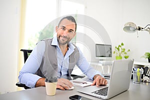 Portrait of handsome trendy casual mid age business man in office desk with laptop computer