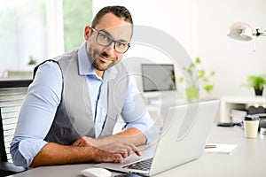 Portrait of handsome trendy casual mid age business man in office desk with laptop computer