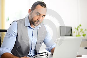 Portrait of handsome trendy casual mid age business man in office desk with laptop computer