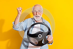 Portrait of handsome trendy cheerful grey-haired man driving having fun new car buy isolated on vivid yellow color