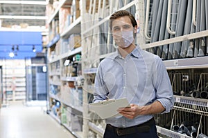 Portrait of handsome warehouse wears medical mask during epidemy. Worker in a cash and carry wholesale store