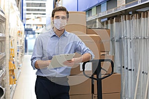 Portrait of handsome warehouse wears medical mask during epidemy. Worker in a cash and carry wholesale store