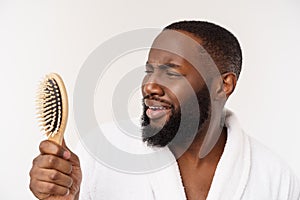 Portrait of handsome young african american man combing his hair in bathroom. Isolated over white background