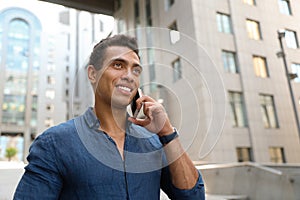 Portrait of handsome young African-American man talking on mobile phone outdoors