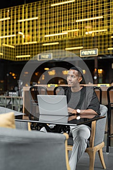 Portrait of handsome young African man using laptop computer in coffee shop