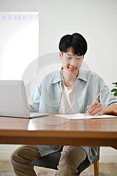 Portrait, Handsome young Asian male college student doing homework, taking notes