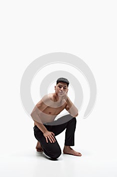 Portrait of handsome young asian man posing shirtless in pants against white studio background. Muscular fit body shape