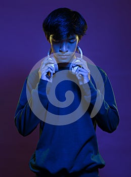 Portrait of handsome young asian man wearing headphone in neon light