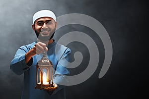 Portrait of handsome young asian muslim man with beard holding arabic lantern and smile