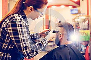 Portrait of handsome young bearded caucasian man getting trendy haircut in modern barber shop.