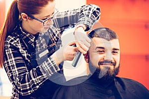 Portrait of handsome young bearded caucasian man getting trendy haircut in modern barber shop.