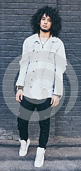 Portrait of handsome young black man with curly afro hair. Outside. Dressed in a jeans jacket