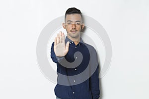 Handsome young business man with open hand doing stop sign with serious expression defense gesture isolated on white background