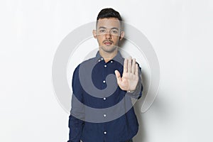 Handsome young business man with open hand doing stop sign with serious expression defense gesture isolated on white background